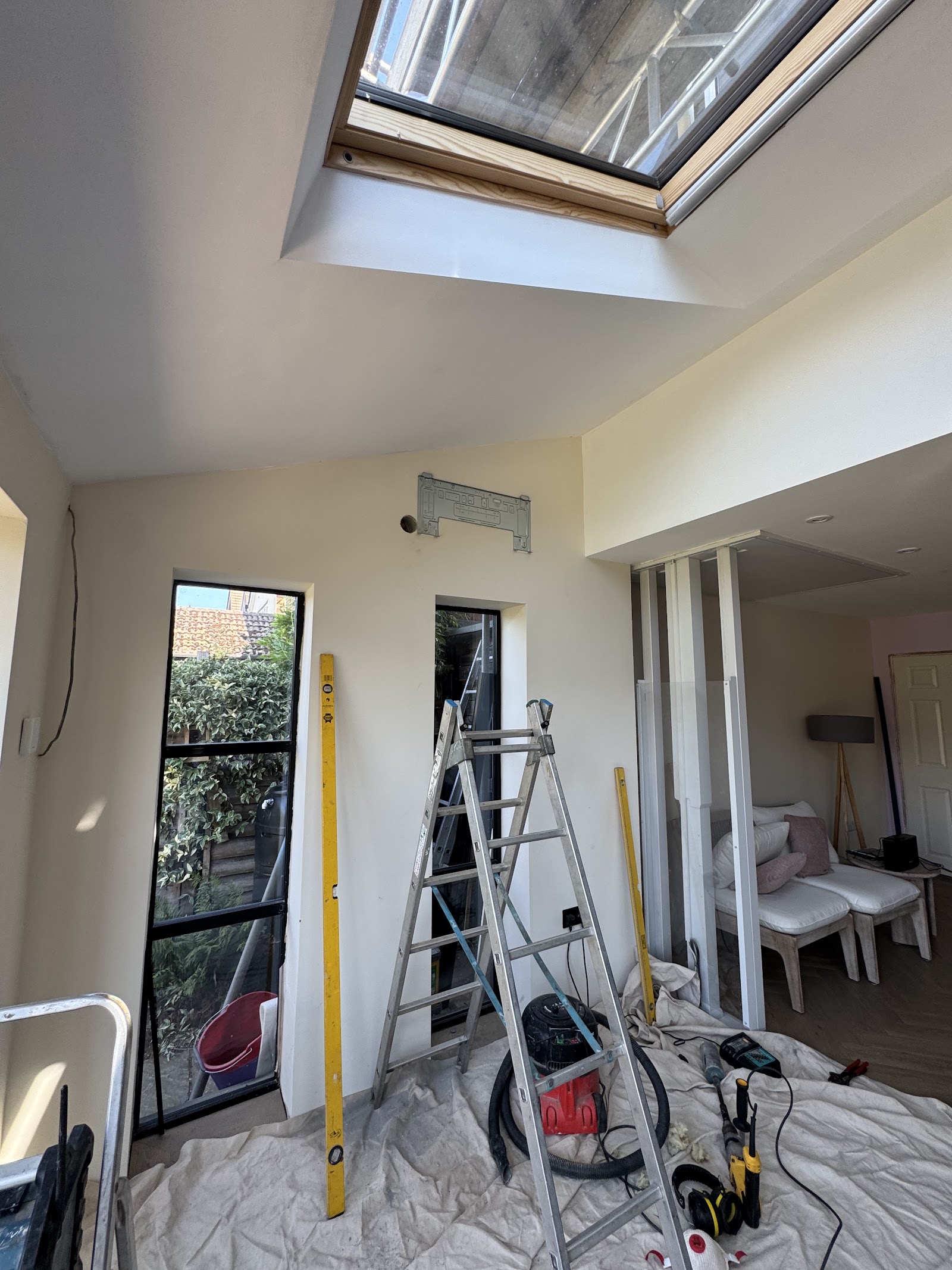 A room refurbishment in progress — new skylight, steelwork and pipework being prepared before finishing.
